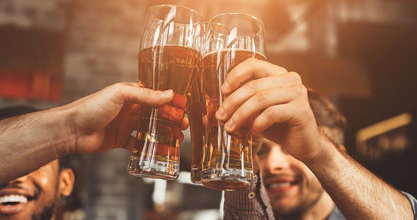 A group of men toast glasses of beer in a pub